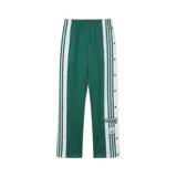 Pantalón deportivo Adidas Adibreak de color verde con bandas laterales blancas y botones a presión en los laterales. Cuenta con cintura elástica y el clásico logo de la marca bordado.