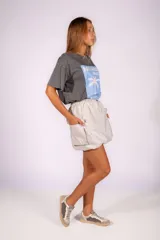 Falda corta negra de material ligero y brillante, con cintura elástica fruncida y bolsillos cargo frontales. El ruedo tiene un efecto abullonado o globo.