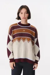 Buzo de tejido de punto con diseño geométrico y combinación de colores en contraste. Presenta cuello redondo, mangas largas y corte oversized.