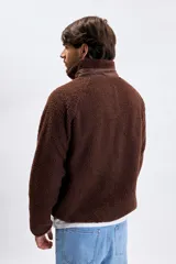 Campera de sherpa color marrón con cierre frontal completo, cuello alto y bolsillo en el pecho con cierre.
