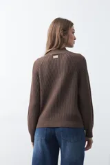 Polera de punto color marrón, con cuello alto y diseño de trenzas verticales en el frente y tejido acanalado en las mangas. Presenta mangas raglán y terminaciones acanaladas en puños y ruedo.