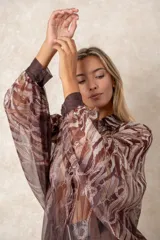 Camisa oversize de gasa con estampado de cadenas en tonos bordó y rosado. Presenta cuello clásico, cierre frontal con botones y mangas largas con puños abotonados.
