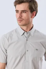 Camisa de manga corta de algodón en color celeste con microdiseño geométrico a cuadros, cuello camisero y bolsillo frontal con logo bordado.