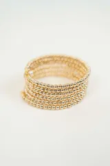 Brazalete dorado con múltiples hilos de cuentas redondas.