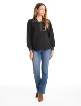 Buzo de modal color negro con cuello solapa y escote en V con botones a presión. Presenta mangas largas con puños elastizados y detalles de textura en el cuello y puños.