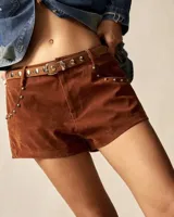 Short de gamuza color marrón con detalle de tachas metálicas en los bolsillos laterales. Incluye un cinturón fino de cuero a tono con hebilla metálica.