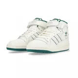 Championes adidas Forum Mid de corte medio, color blanco con detalles en verde oscuro en el cuello, las tres tiras laterales, el logo del trébol y la suela. Presentan cierre de cordones y tira de velcro en el tobillo.