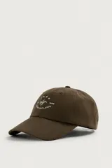 Gorra de seis paneles de color marrón oscuro, confeccionada en tejido de algodón. Cuenta con un diseño bordado en la parte frontal que incluye el texto "TEXAS OUTLAWS", la fecha "1999" y una silueta con estrellas.
