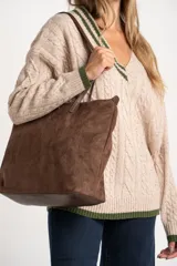 Sweater de lana y nylon color beige jaspeado, con diseño de punto trenzado (cable knit) en todo el cuerpo y mangas. Presenta cuello en V con ribete de dos franjas verdes y puños y bajo con ribete verde liso.