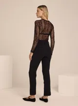 Pantalón negro de crepe con diseño entallado, cinturilla con trabillas y hebilla ajustable, cintura alta, cierre de cremallera frontal y cuatro bolsillos.