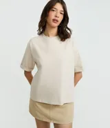 Remera básica de algodón color beige, de corte oversized, con cuello redondo y mangas cortas amplias con dobladillo.