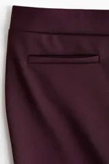 Pantalón de tiro alto confeccionado en punto roma, con diseño ajustado en la parte superior y piernas acampanadas. Presenta bolsillos insertados decorativos en la parte frontal.