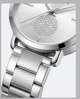 Reloj de pulsera analógico Mini Focus con caja y malla de acero inoxidable en color plateado. Presenta una esfera minimalista con un detalle circular texturizado en el centro y cierre de seguridad plegable con botón de liberación.