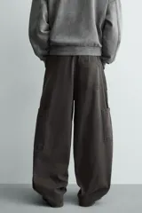 Pantalón de corte relaxed fit confeccionado en algodón, color gris oscuro. Presenta bolsillos delanteros, bolsillos laterales tipo cargo en las perneras y cierre frontal con cremallera y botón.