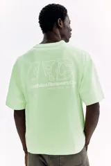 Remera de algodón verde menta de punto pesado, con corte holgado, hombros caídos, cuello redondo y estampa numérica frontal.