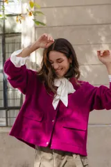 Chaqueta de lana afieltrada en color fucsia, con corte holgado, cierre frontal con broches, bolsillos delanteros y diseño con apertura en la espalda.