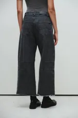 Pantalón de jean negro de pierna ancha, tiro medio y pinzas marcadas, con lavado stonewash y botamanga deshilachada.