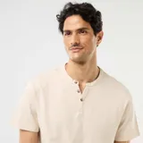 Remera de manga corta color beige, con cuello tunecino y cartera con botones frontales.