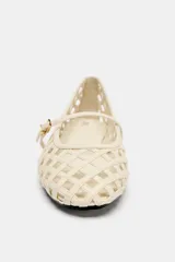 Zapato plano tipo bailarina color crema, con diseño trenzado calado en todo el cuerpo y punta redonda. Posee una delgada tira con hebilla metálica dorada sobre el empeine.