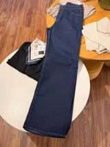 Pantalón de jean corte wide leg, color azul oscuro, con costuras en hilo color camel y cierre frontal con botón metálico.