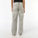 Jean de corte baggy en color gris con efecto lavado ácido. Presenta bandas laterales en tono plateado brillante y diseño de cinco bolsillos con cierre de botón y cremallera.