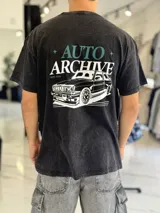 Remera oversize negra con efecto gastado, de manga corta, con estampa en la espalda que incluye texto y la ilustración de un auto clásico.