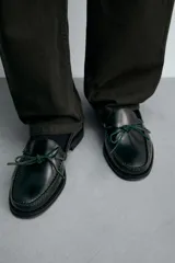 Mocasín de vestir fabricado en piel con acabado brillante, presenta un detalle de lazo en el empeine y suela a contraste con ligero tacón.