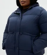 Campera puffer acolchada azul marino de Ashua, con capucha, mangas largas, bolsillos frontales, cordón regulable en la cintura y cierre frontal con broches a presión.