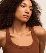 Musculosa básica de calce ajustado confeccionada en tejido rib acanalado. Presenta escote redondo y breteles medios, ofreciendo un diseño versátil y cómodo.
