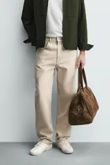 Pantalón jeans de corte recto y tiro medio, confeccionado en denim de algodón color beige con efecto lavado, bolsillos clásicos y cierre frontal con cremallera y botón.