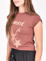 Remera de manga corta color lila claro, con cuello redondo y bordes deshilachados. Presenta un estampado central de dos leopardos dentro de un marco cuadrado, con los patrones de sus manchas en forma de corazones.