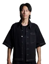 Camisa negra de denim, corte boxy, manga corta y costuras blancas a contraste.