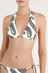 Top de bikini halter con estampado paisley en tonos azules, rojos y marrones sobre fondo blanco. Cuenta con tiras para atar al cuello y en la espalda, y detalle de argolla metálica en el centro con cordones ajustables terminados en terminales metálicas.