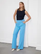 Pantalón naranja de crepe elastizado, corte recto, con bolsillos delanteros y apliques de botones metálicos.