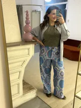 Pantalón cargo de tiro alto, color azul vibrante con estampado de círculos y estrellas en tonos morados y blancos. Presenta un calce ancho y holgado, con elástico ajustable en la parte trasera de la cintura y frunce en los tobillos que puede ajustarse o dejarse suelto.