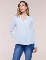 Blusa celeste fluida de viscosa, con escote en V y cuello mao, mangas largas y pliegue central en el delantero.