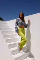 Blusa corta de algodón con estampado de hojas en tonos azul, blanco y verde. Tiene escote en V y mangas largas con puños acampanados.