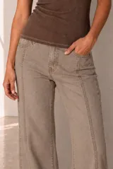 Jean de corte flare color beige, con tiro medio y botamanga ancha deshilachada.