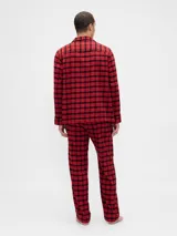 Pijama de hombre compuesto por una camisa de manga larga y un pantalón largo, ambos confeccionados en tela de franela con estampado de cuadros en tonos rojo y negro. La camisa cuenta con cierre frontal de botones y cuello clásico, mientras que el pantalón presenta un corte recto y cómodo.