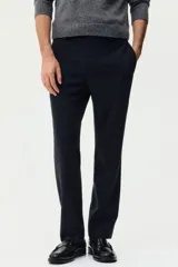 Pantalón sastrero de corte slim fit y color negro, con cierre frontal de botón, bolsillos laterales al bies y bolsillos posteriores ojalados. Cuenta con trabillas para cinturón y pretina elástica en la parte posterior.