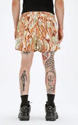 Short de baño de calce regular con estampado abstracto en tonos verdes, naranjas y marrones. Posee cintura elástica con cordón de ajuste negro y un pequeño logo negro en el lateral inferior derecho.