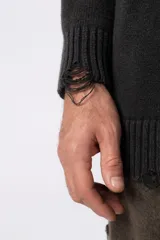 Sweater de punto grueso color negro con efecto gastado, cuello redondo, mangas largas y detalles de roturas en puños y ruedo. Presenta un diseño con letras bordadas al tono en el frente.