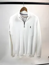 Buzo de punto color crudo, con medio cierre frontal y cuello alto.