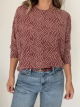 Buzo de tejido de punto con diseño de estampado tipo cebra y sutiles hilos dorados integrados. Presenta cuello redondo, mangas largas y un corte holgado.