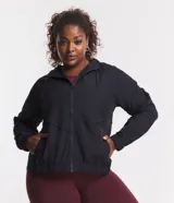 Campera rompeviento deportiva de color negro, con cierre frontal de cremallera, capucha ajustable con cordón, bolsillos laterales y ruedo elástico. Presenta recortes delanteros y diseño de manga larga.