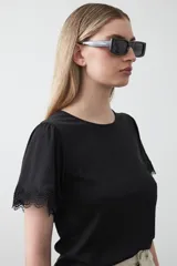 Remera de tejido acanalado color blanco, con cuello redondo y mangas cortas que presentan un detalle de terminación en puntilla en los bordes.