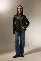 Sobrecamisa de cuero sintético en color negro, con cuello clásico, cierre frontal mediante botones metálicos y dos bolsillos frontales con solapa. Presenta costuras a la vista y mangas largas con puños abotonados.