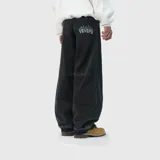 Pantalón de jean estilo baggy, color negro con efecto lavado. Presenta un corte ultra holgado y un bordado en el bolsillo trasero con el nombre de la marca y detalles de llamas.