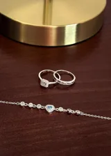 Set de dos anillos de plata 925, uno con diseño de medio sin fin con incrustaciones de zirconias y otro modelo cintillo con zirconia central de corte cuadrado rodeada de piedras pequeñas.
