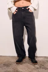 Jean de corte baggy con diseño barrel, tiro medio y acabado en color negro lavado. Presenta cierre frontal con botón y bolsillos laterales y traseros.